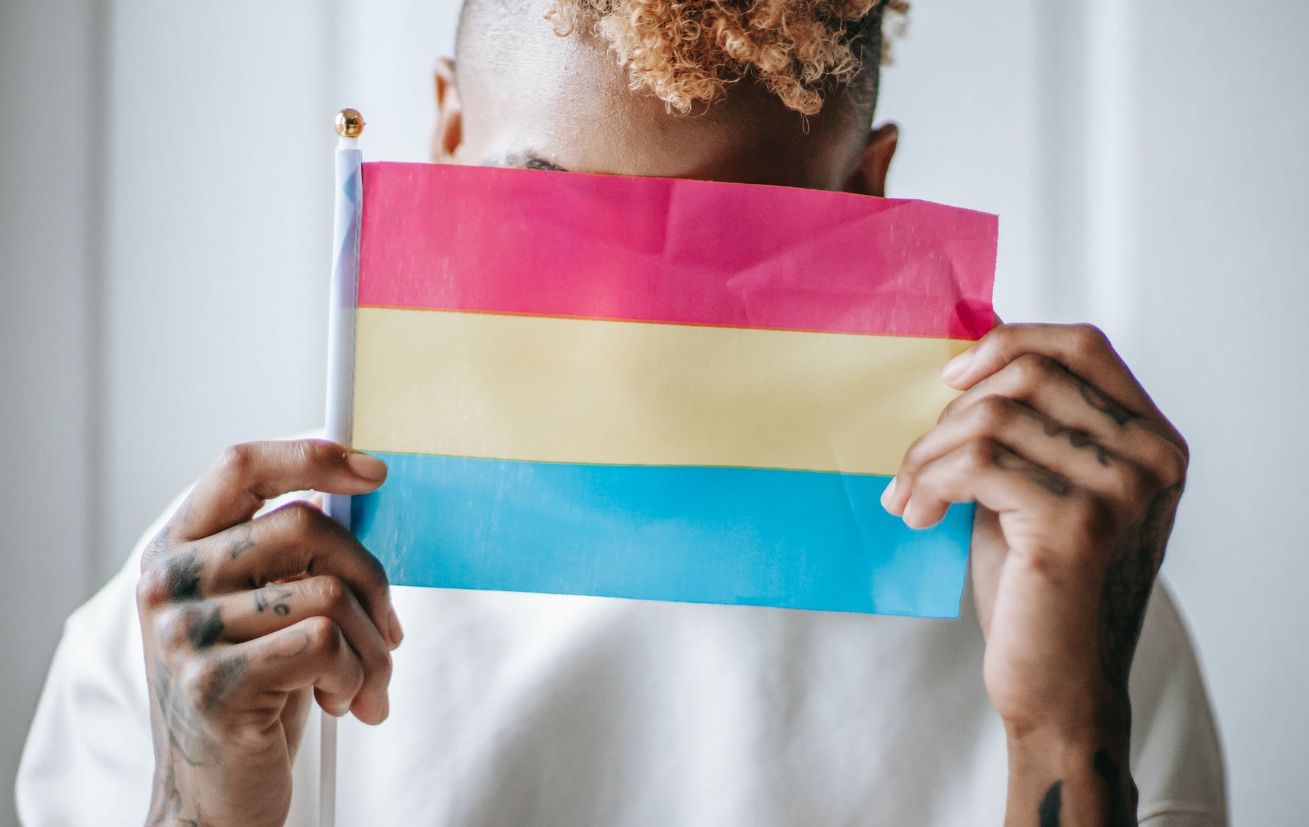 Black transgender person holding lesbian gay bisexual transgender pride flag